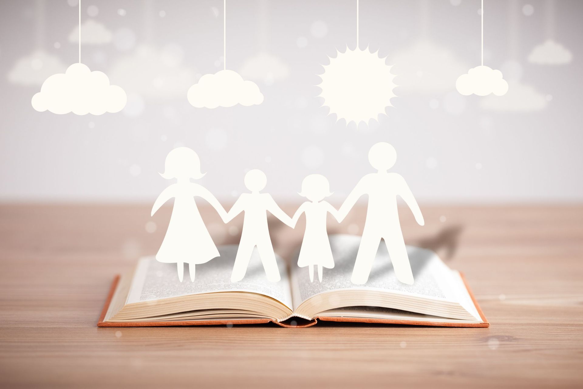 Un recorte de papel de una familia está sentado encima de un libro abierto.